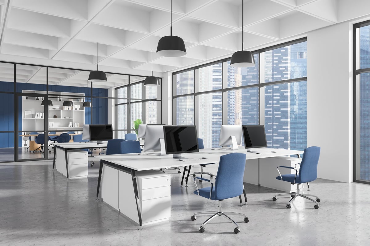 Contemporary office interior with ergonomic furniture, blue chairs, desks, and computers in a spacious area with large windows