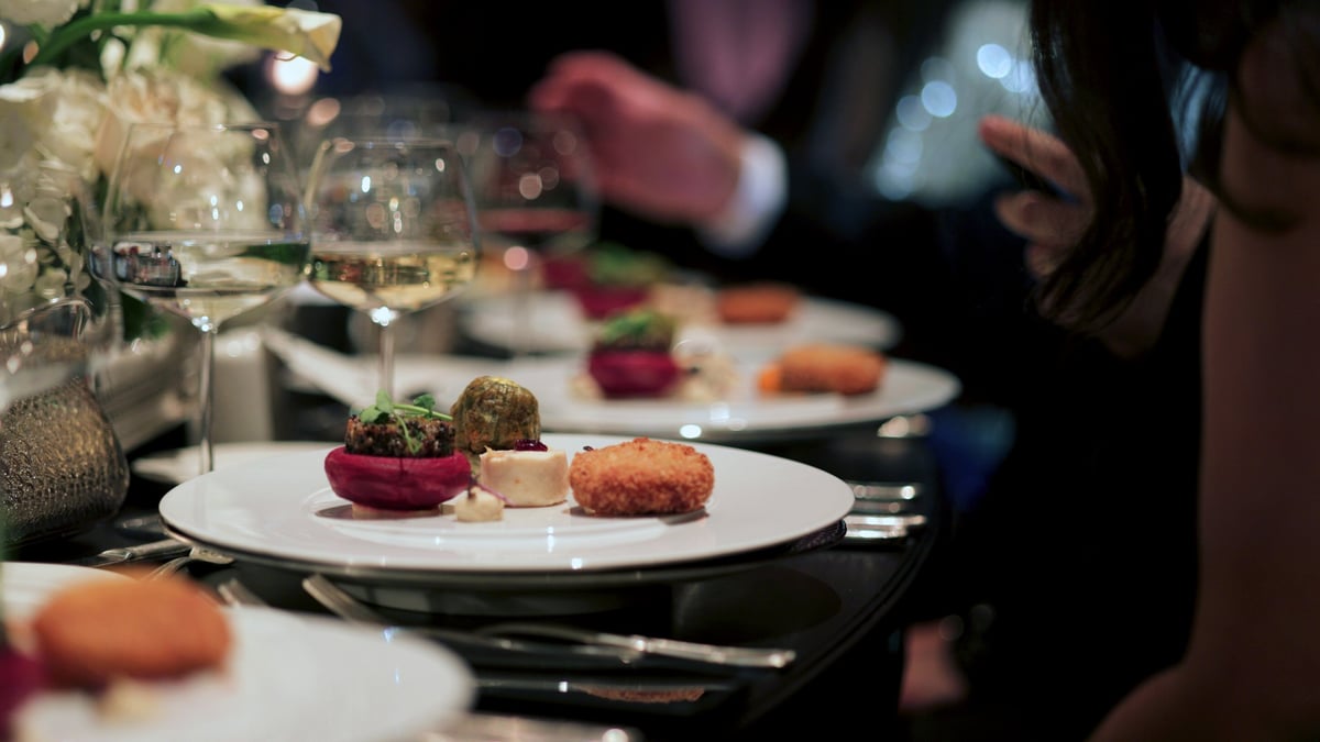 A beautifully plated gourmet dish served at a sophisticated event, accompanied by fine wine and elegant table settings