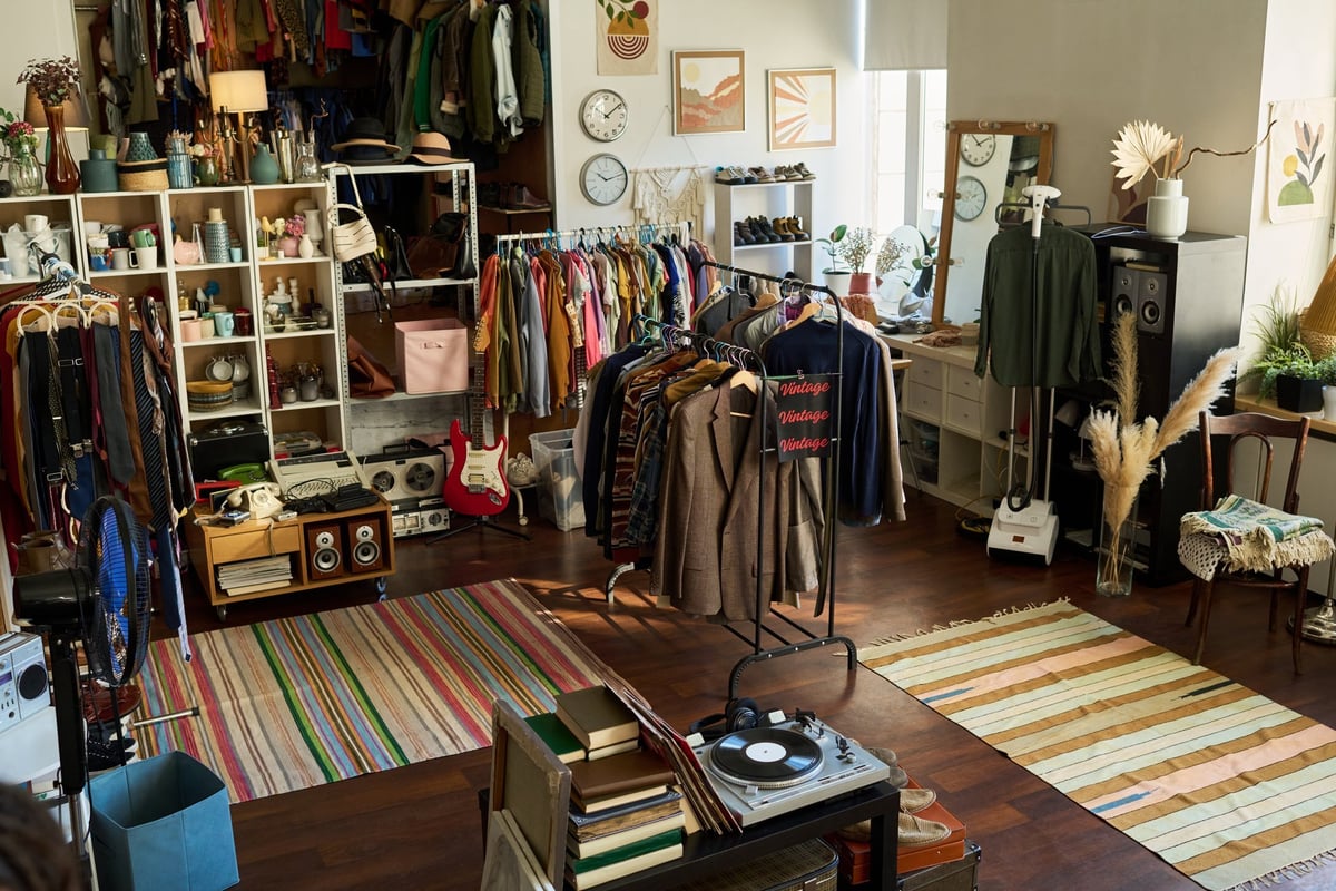 Vintage clothing and accessories displayed on racks and shelves in thrift shop interior